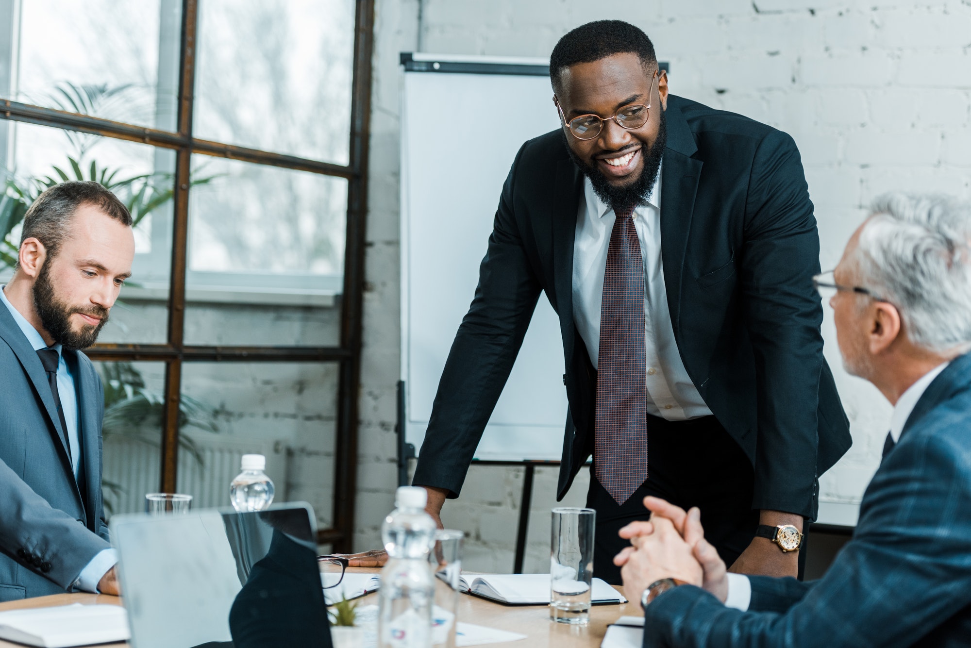 selective focus of cheerful african american business coach smiling near coworkers